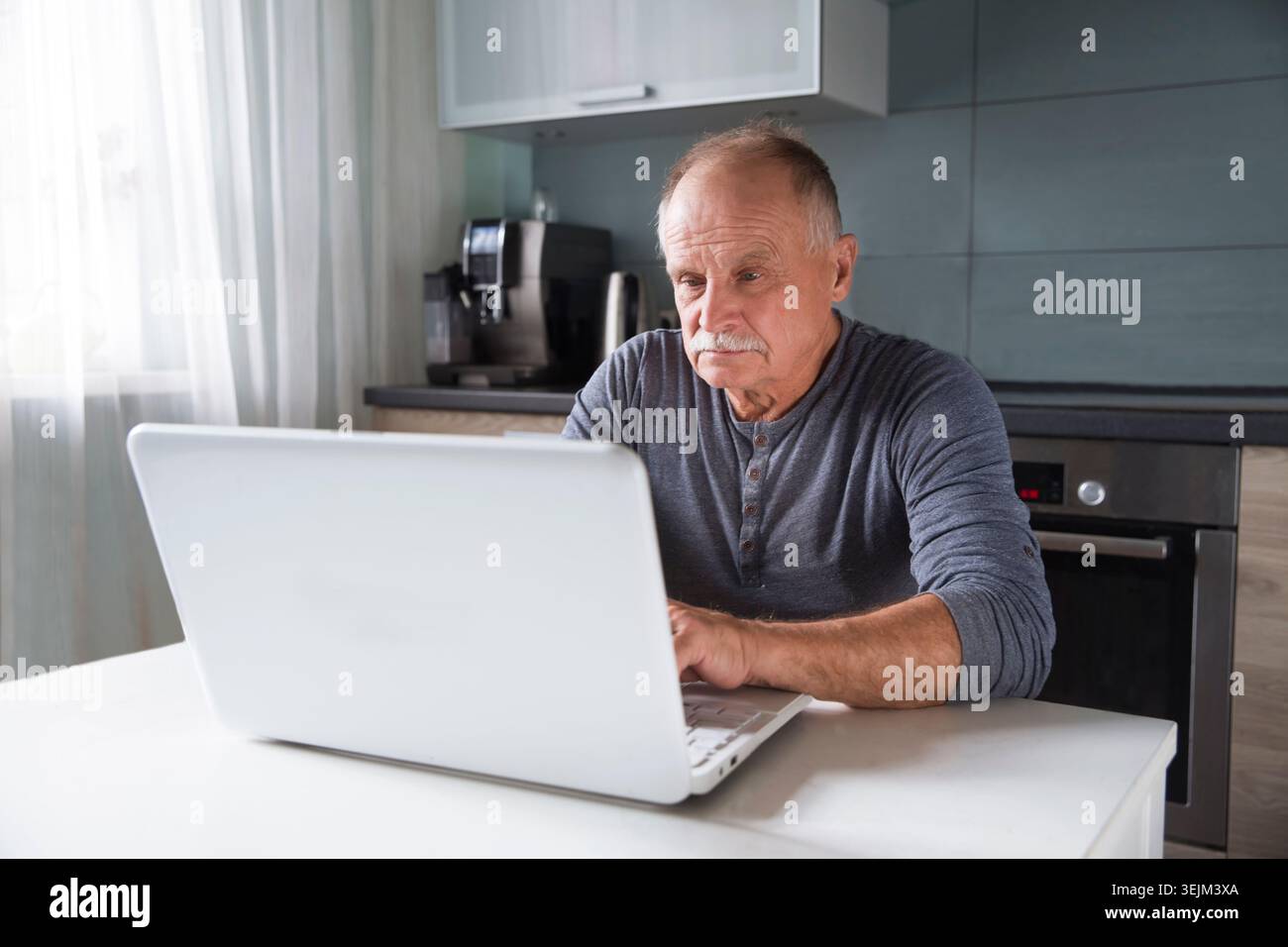 Senior man using laptop at home. Stock Photo
