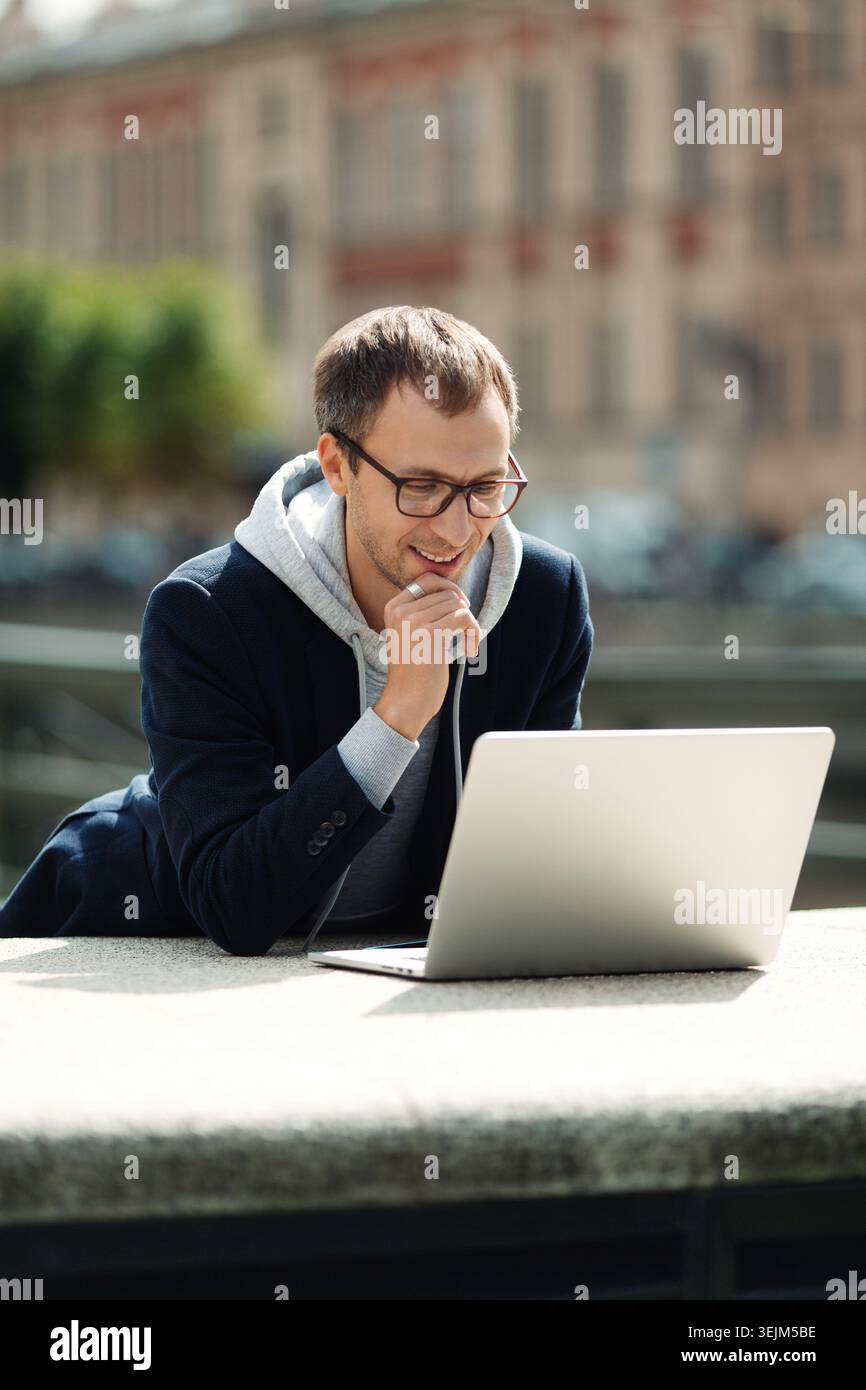 Freelance programmer or web designer read email on laptop computer walking city using 5g internet Stock Photo