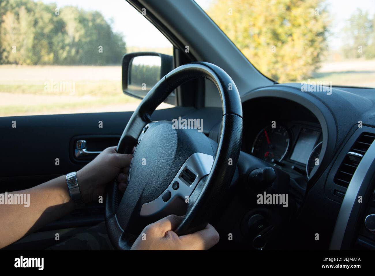 Hands Steering Car on Open Road in Daylight Stock Photo