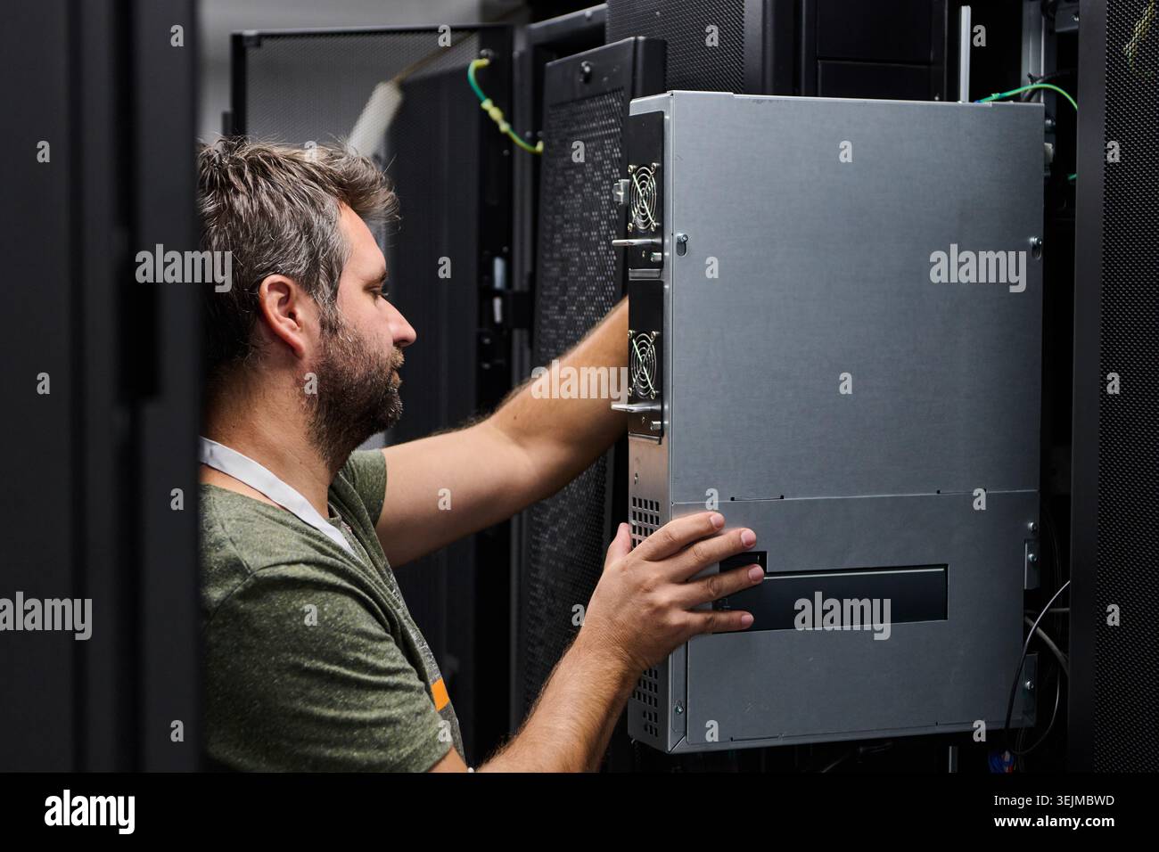 IT technician installing server hardware in a data center during routine maintenance and system upgrade Stock Photo