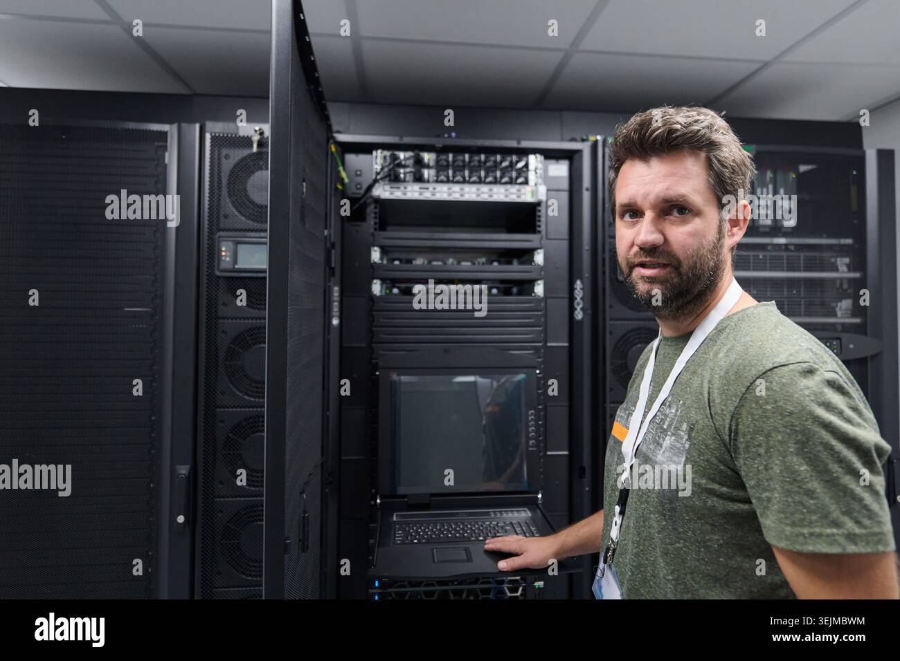 IT technician working in a data center server room checking rack equipment and network systems Stock Photo
