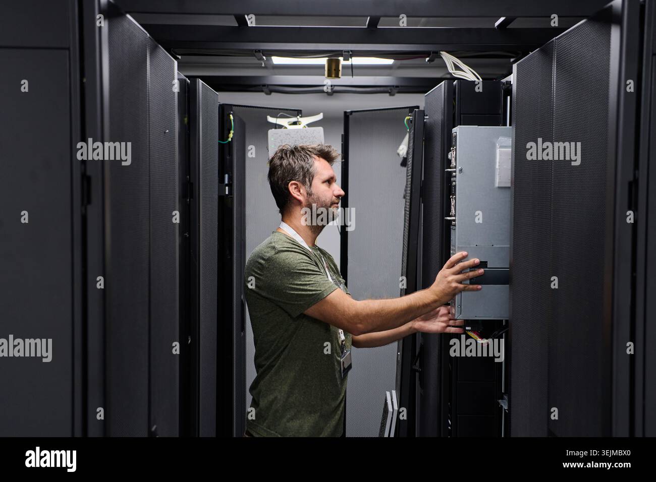 Data center technician installing server hardware in a server rack performing IT maintenance Stock Photo