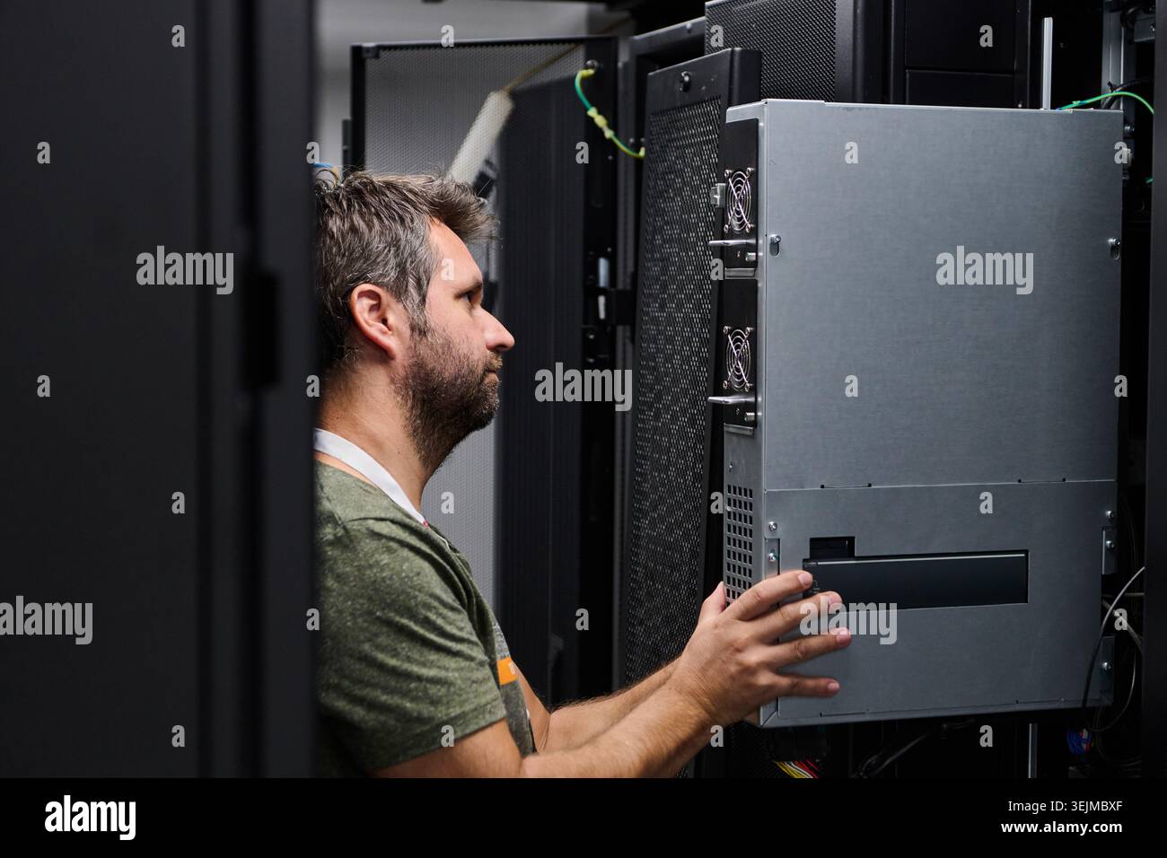 IT technician installing server hardware in a data center server rack performing maintenance and equipment check Stock Photo