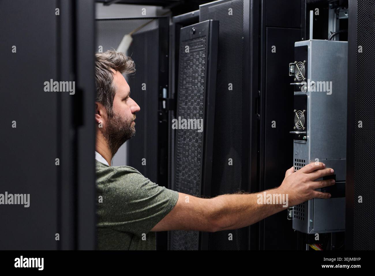 It technician performing server maintenance in a data center server rack with focused attention Stock Photo