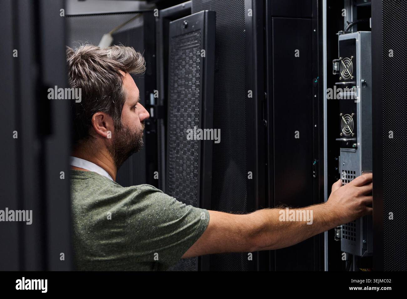 It technician inspecting servers in a data center server rack for maintenance and network support Stock Photo