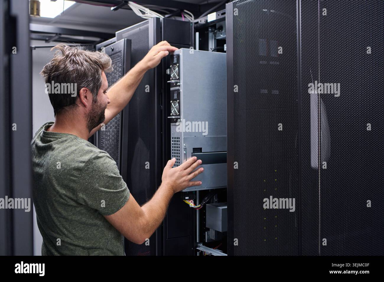 Server technician installing a rack server in a modern data center performing IT maintenance and hardware upgrade Stock Photo