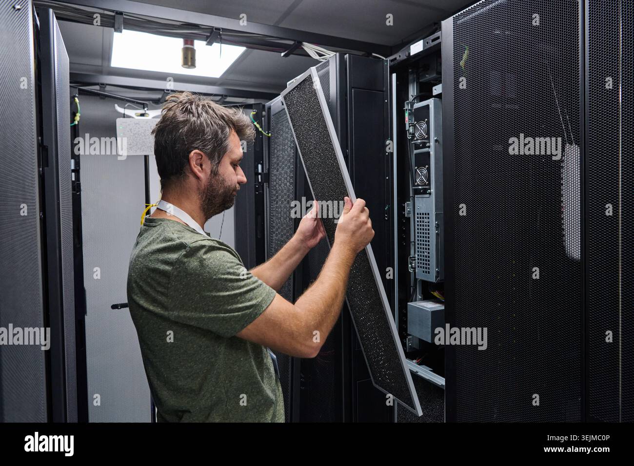 IT technician performing server maintenance in a data center rack replacing air filter panel Stock Photo