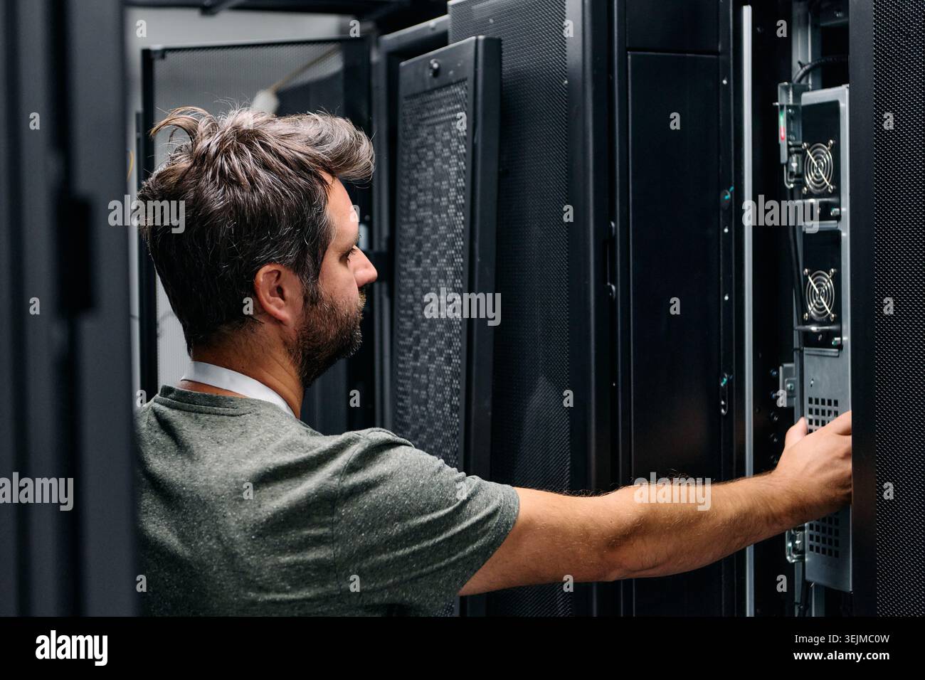 It technician checking servers in a data center rack performing hardware maintenance and network troubleshooting Stock Photo