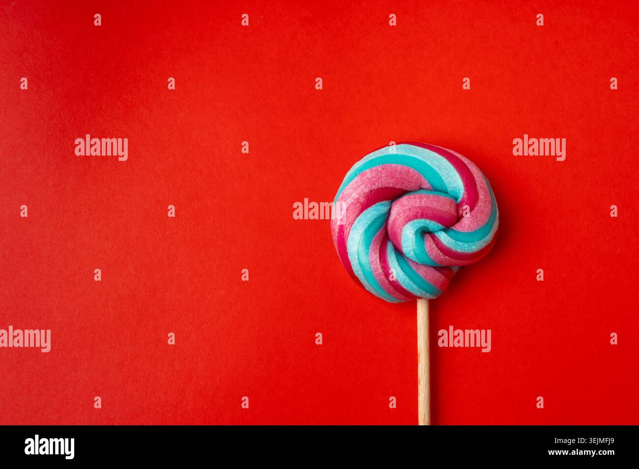 Color lollipop, spiral candy on stick, colorful striped lollypop, round fruit caramel, multicolored confectionery, circle lollipop on red background, Stock Photo
