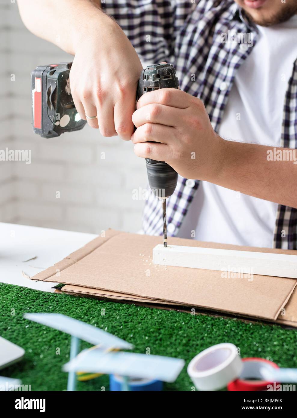 Young man making renewable energy project dummy using drill Stock Photo