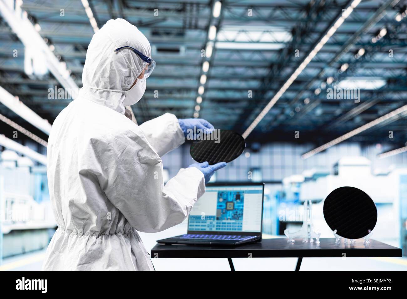 Engineer man processing silicon wafer using EDA software in automated manufacturing facility. Technician inspecting delicate microelectronic hardware with laptop program during quality control process Stock Photo