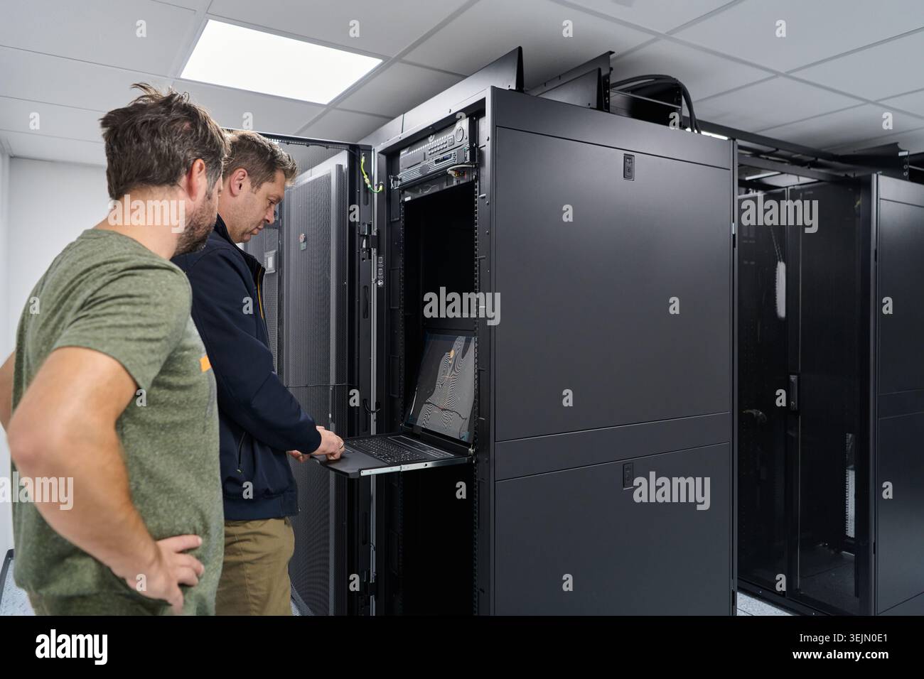 Two IT technicians working on a server rack in a modern data center troubleshooting network hardware Stock Photo