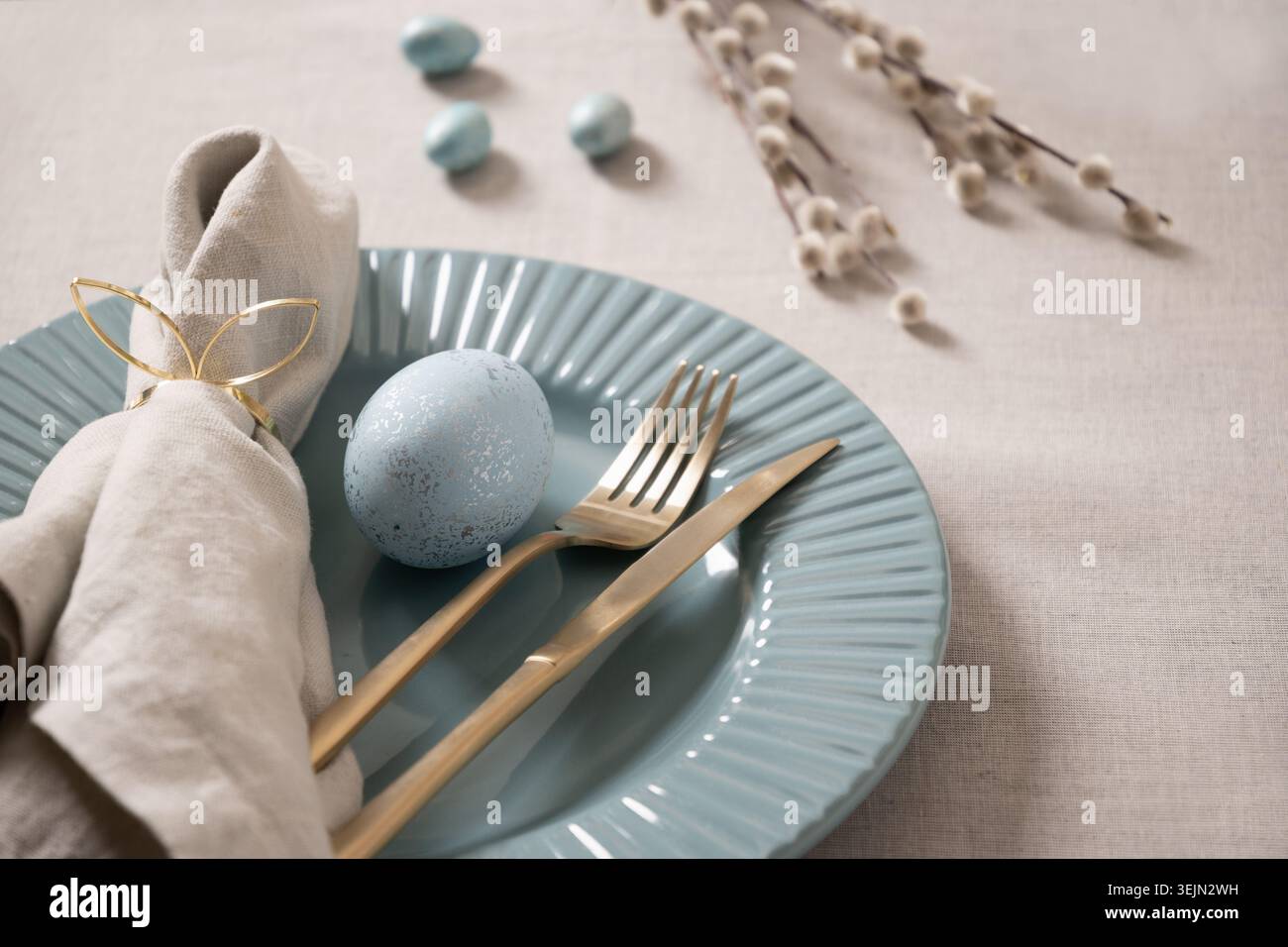 Easter table setting with blue egg and gold cutlery Stock Photo