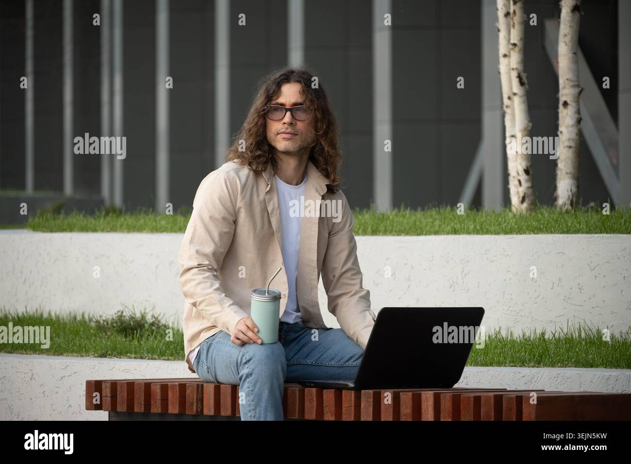 Man Using Laptop on Outdoor Bench for Remote Work Stock Photo