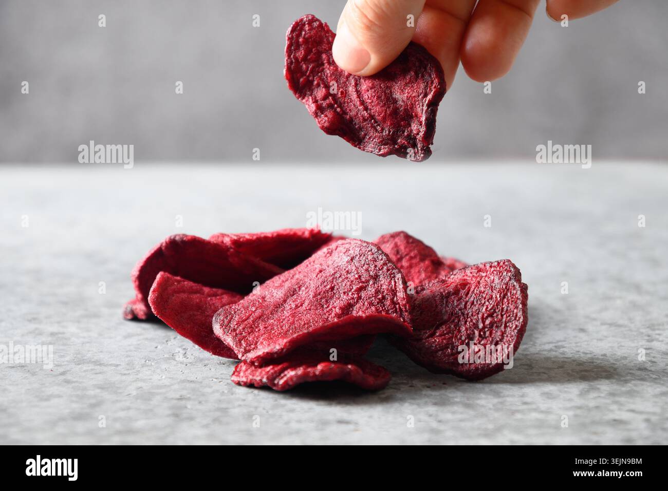 Take a piece vegetable beetroot chips on a gray background. Stock Photo