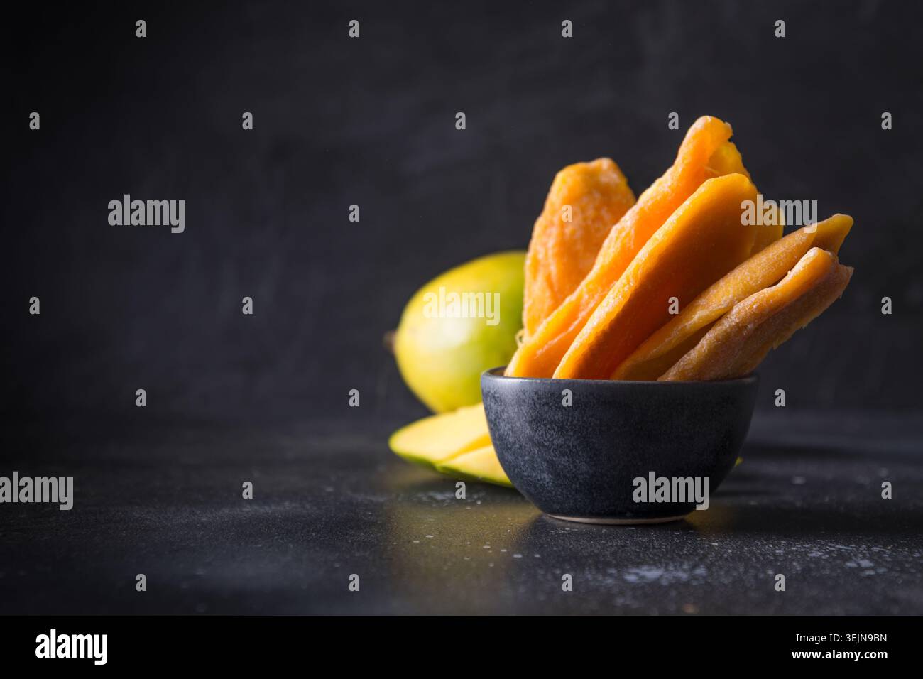 Fresh and dried mango chips on black. Close up. Stock Photo