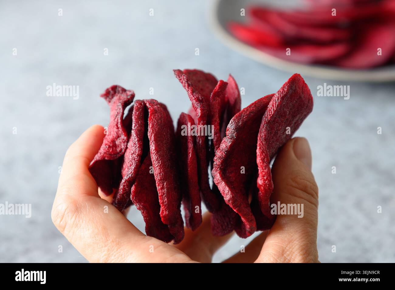 Take a piece vegetable beetroot chips on a gray background. Stock Photo