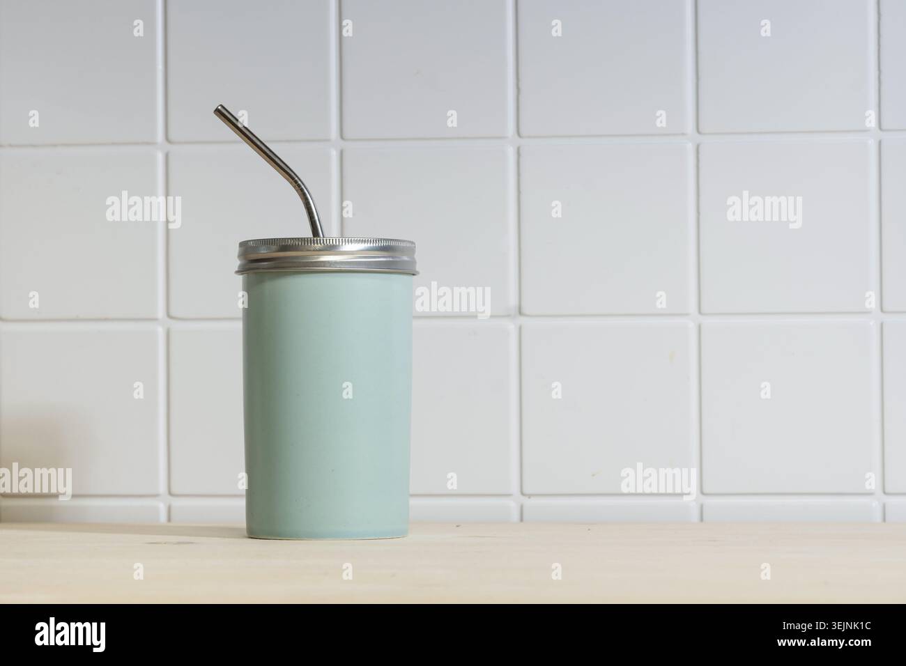 Reusable cup with metal straw on table Stock Photo