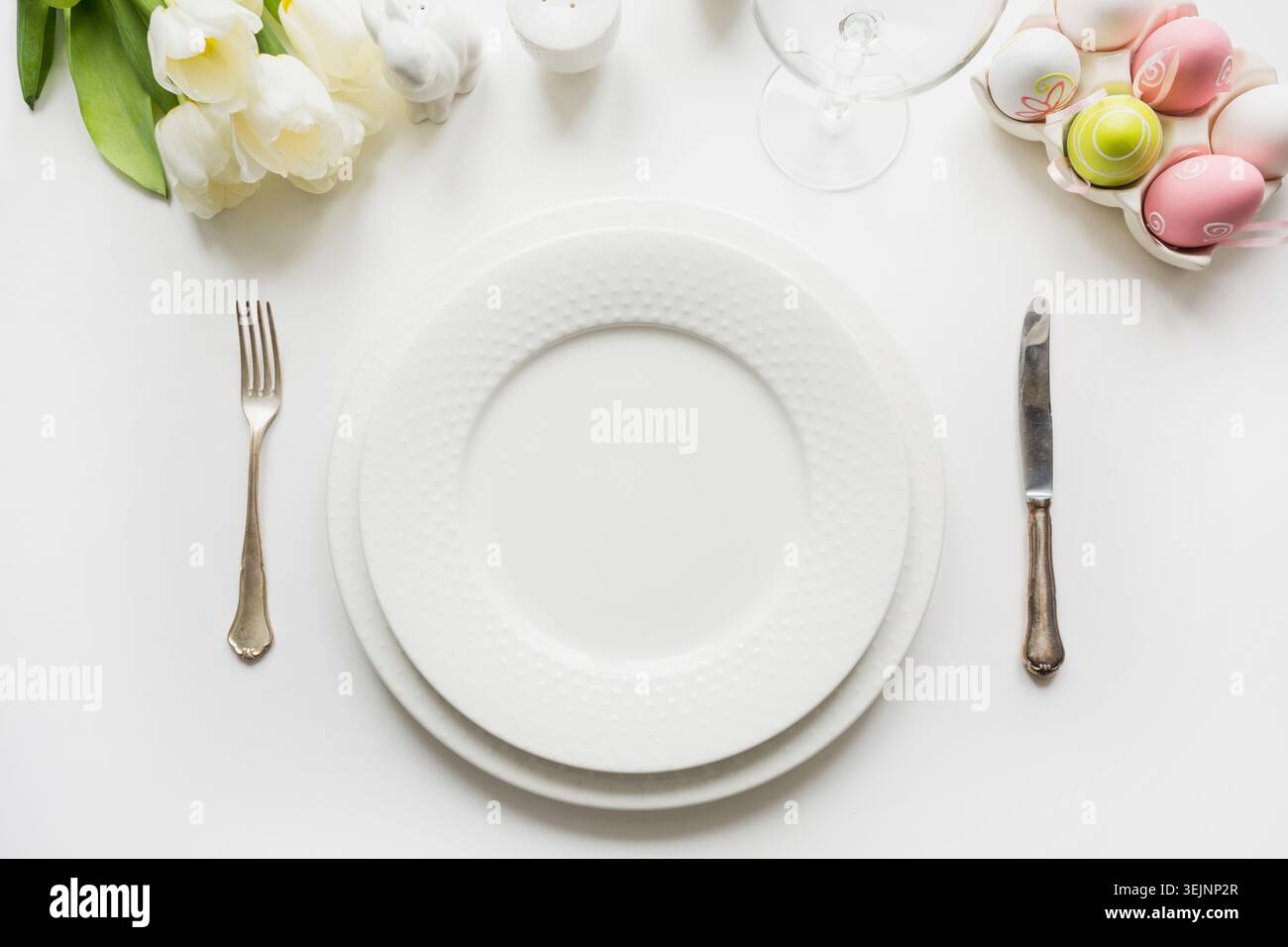 Easter table setting with white tulips, eggs on white table. Top view. Stock Photo