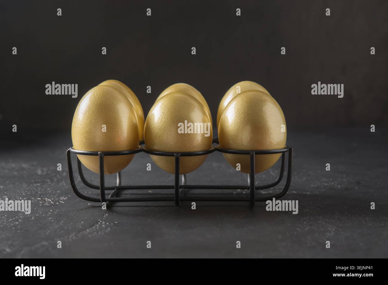 Chicken golden eggs in stand on black background. Easter Stock Photo