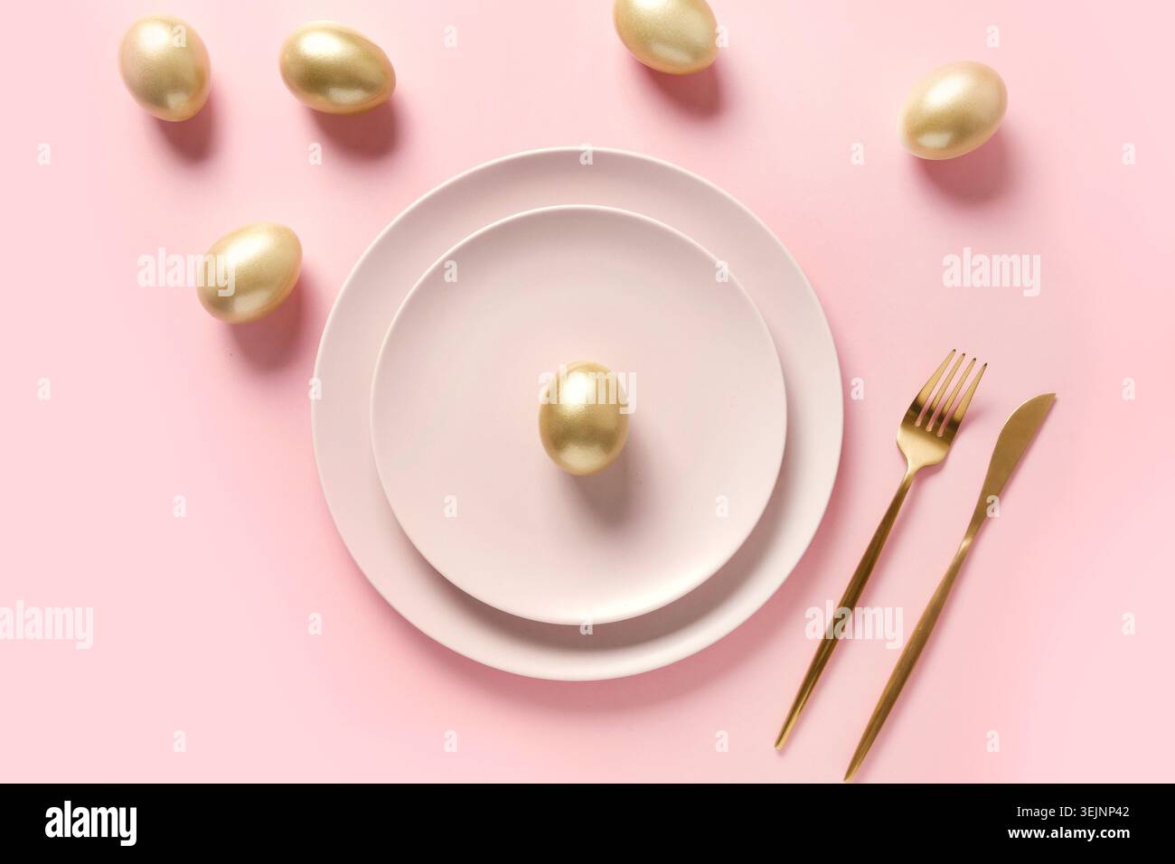 Easter table setting decorated golden eggs on pink. Stock Photo