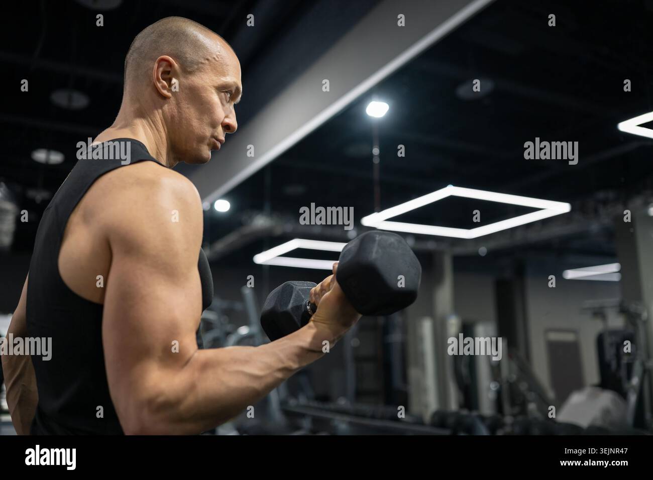 Athletic man doing dumbbell biceps curl strength training Stock Photo