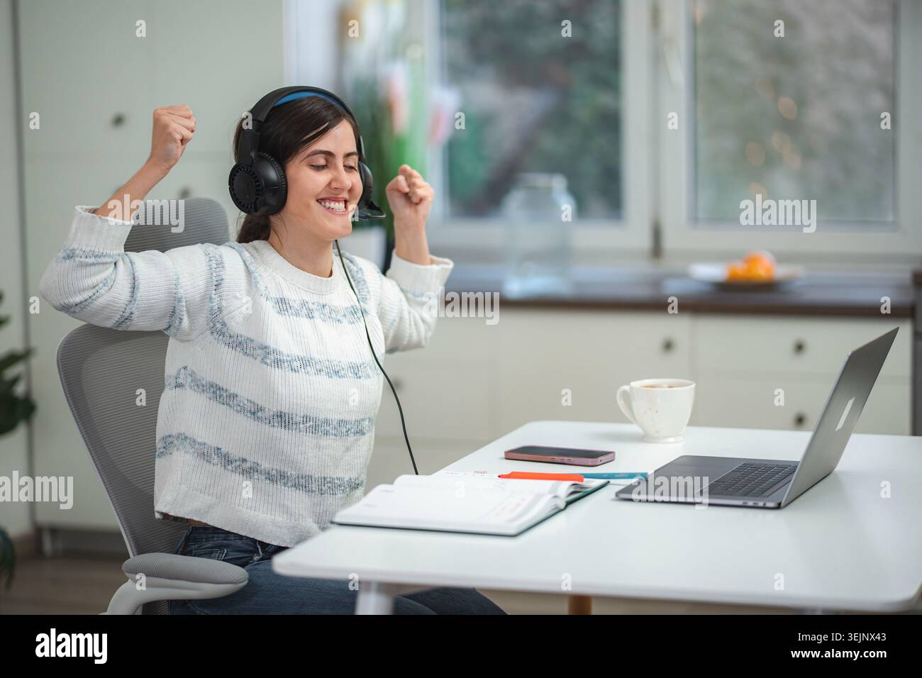 Happy woman celebrating success while working from home Stock Photo