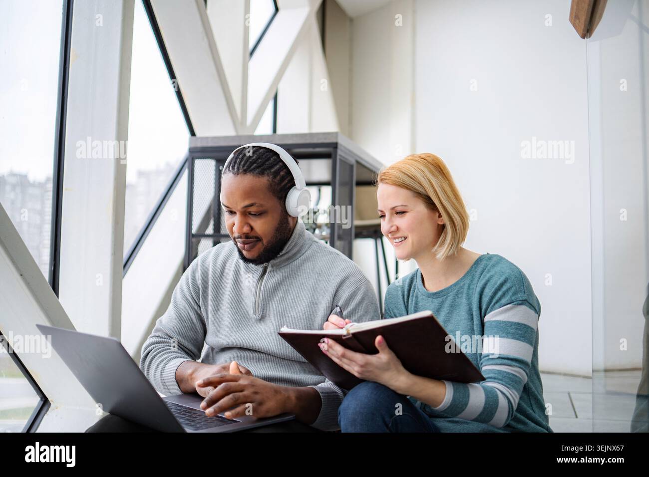 Diverse colleagues collaborating, focused on laptop and notebook Stock Photo