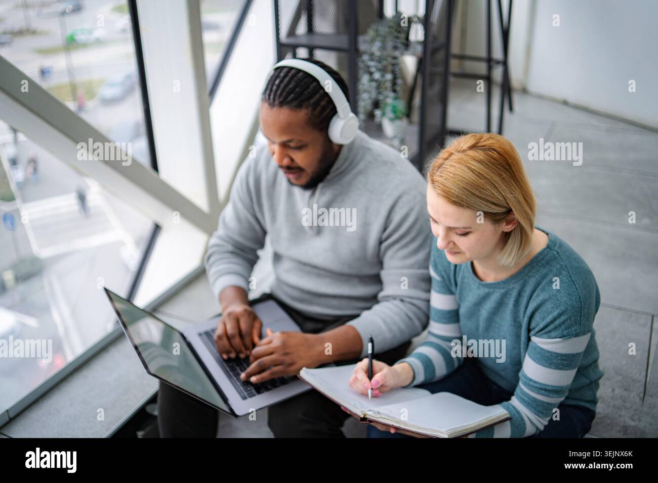 Diverse students collaborating on study project using laptop and notebook Stock Photo