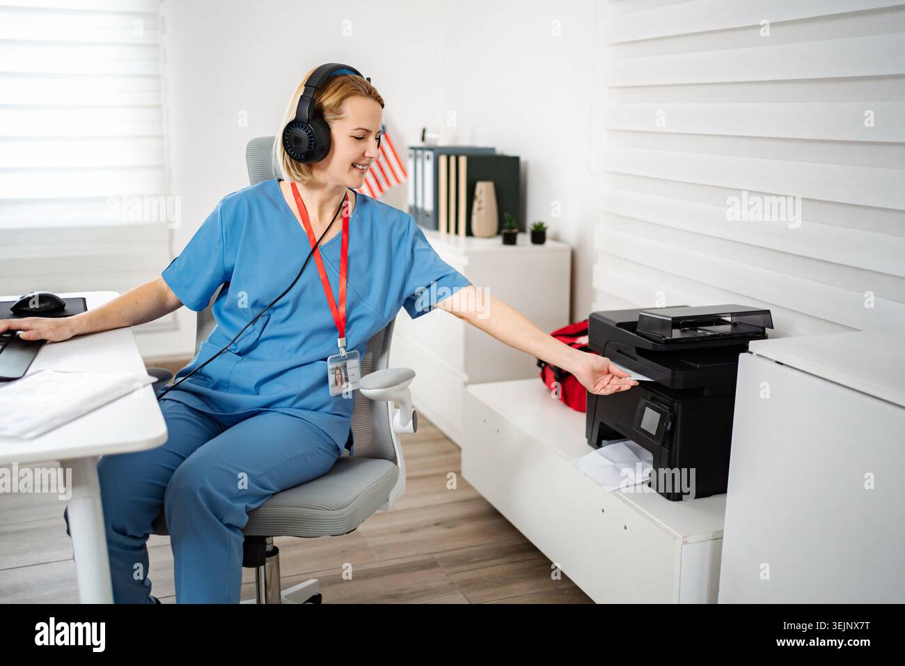 Female nurse working in office multitasking and using printer Stock Photo