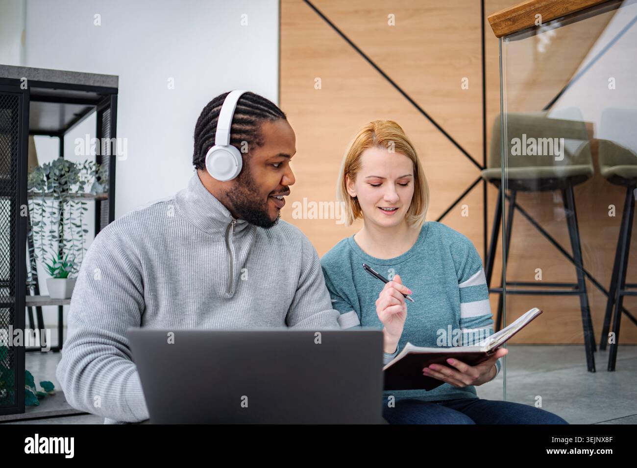 Diverse students collaborating on laptop studying together Stock Photo