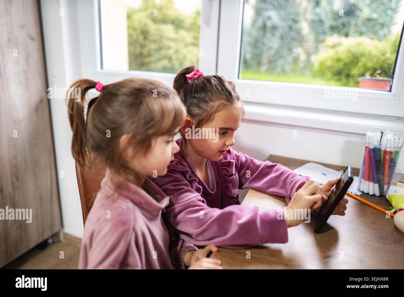Sisters learning at home using digital tablet technology Stock Photo