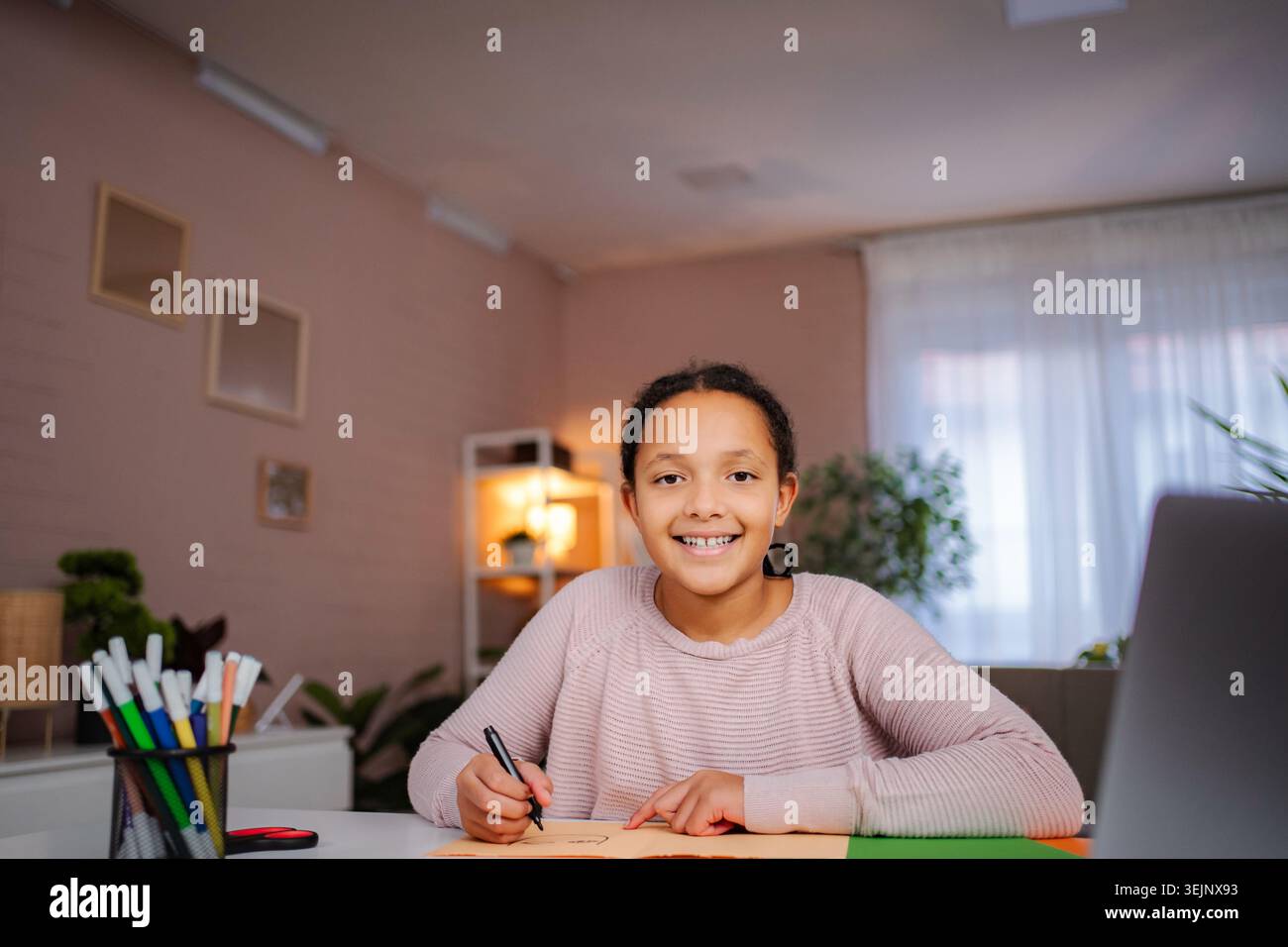 Girl smiling while doing homework at home Stock Photo