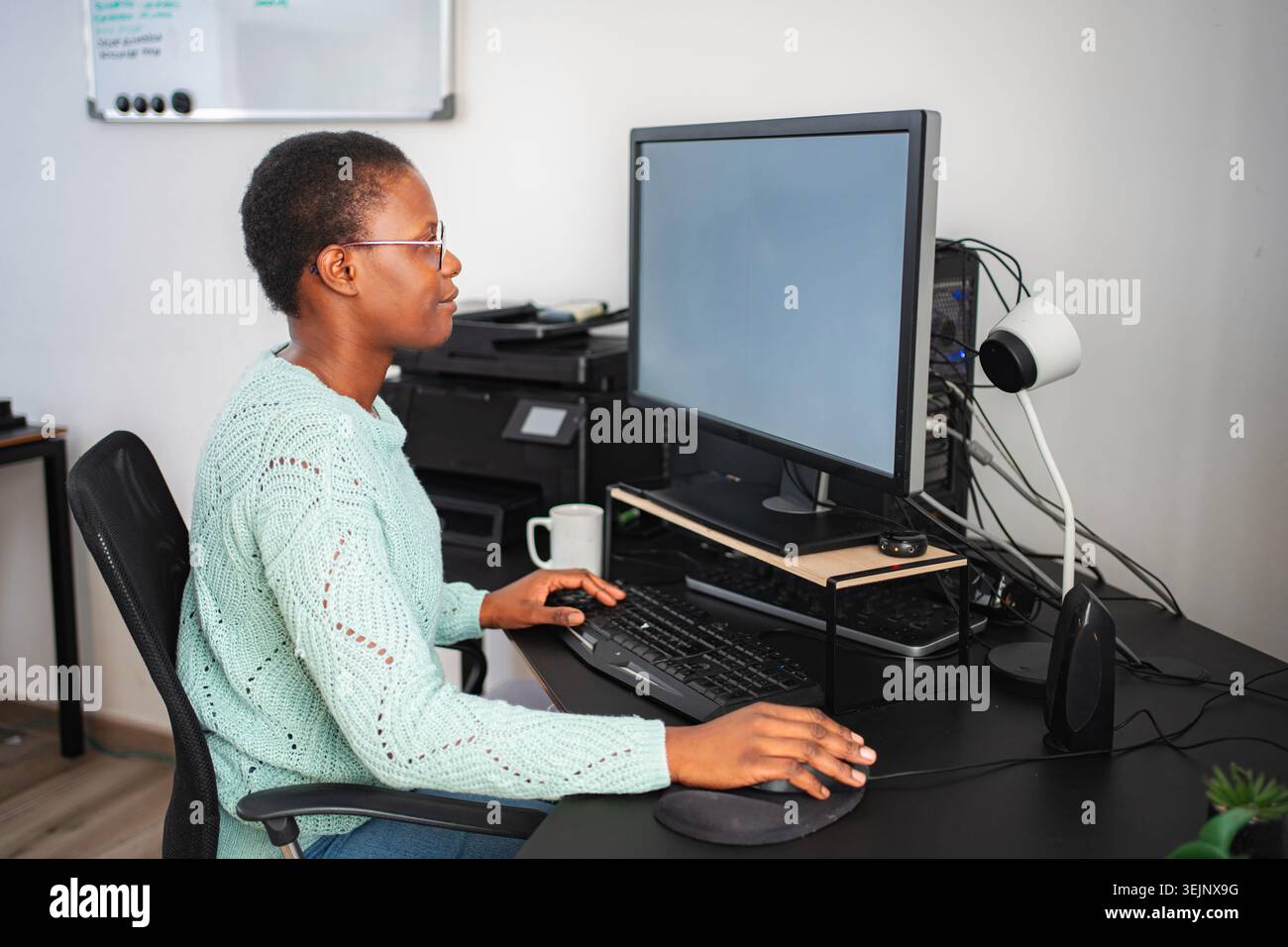 Black woman working from home using computer and keyboard Stock Photo
