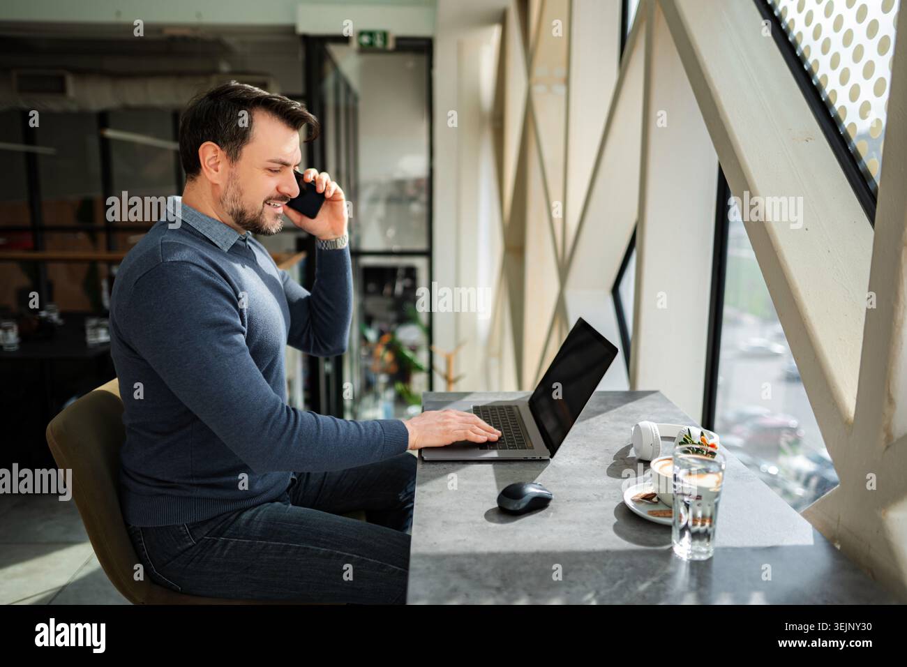 Man working on laptop and talking on mobile phone Stock Photo