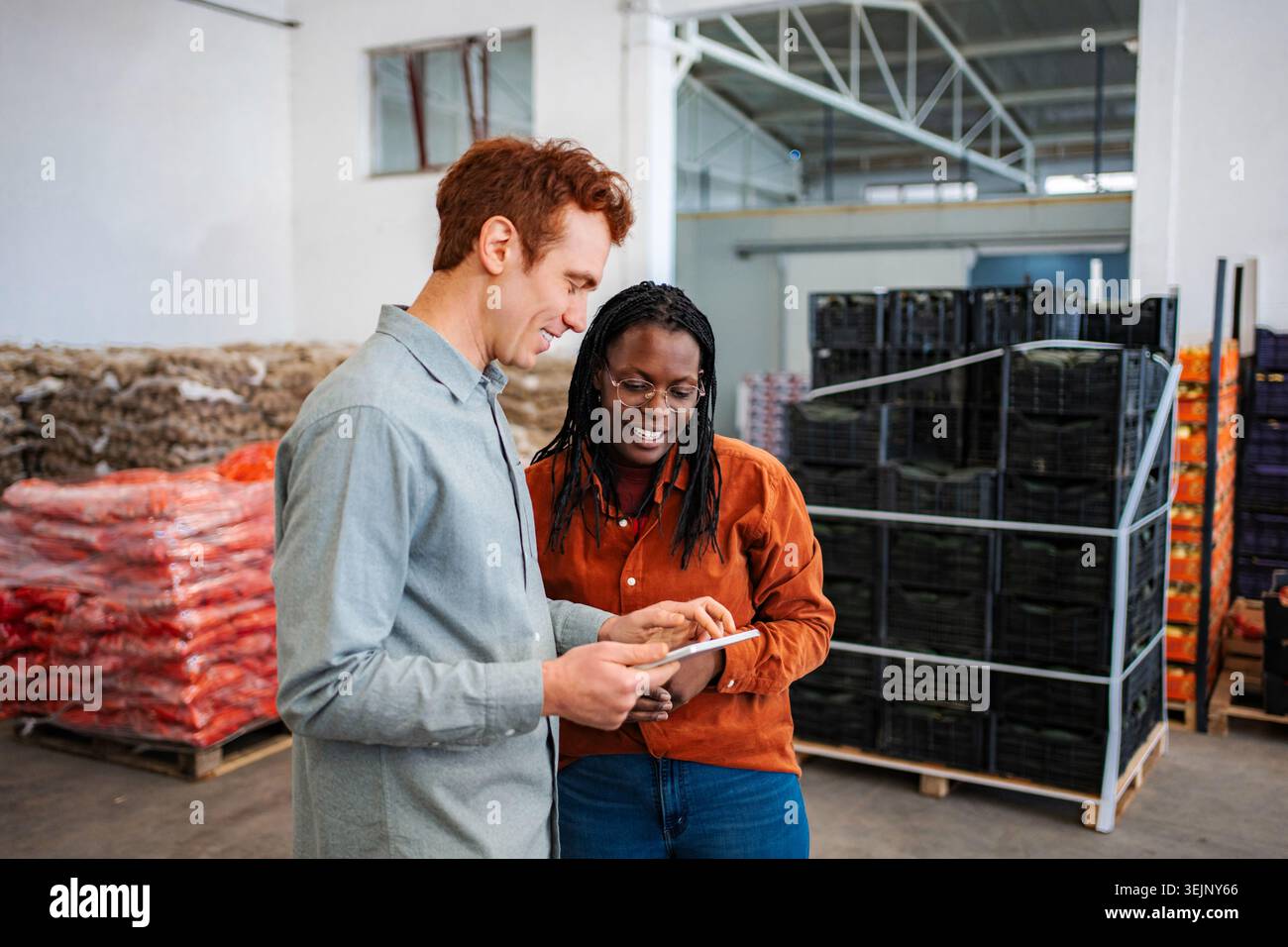 Diverse colleagues managing warehouse inventory using digital tablet Stock Photo