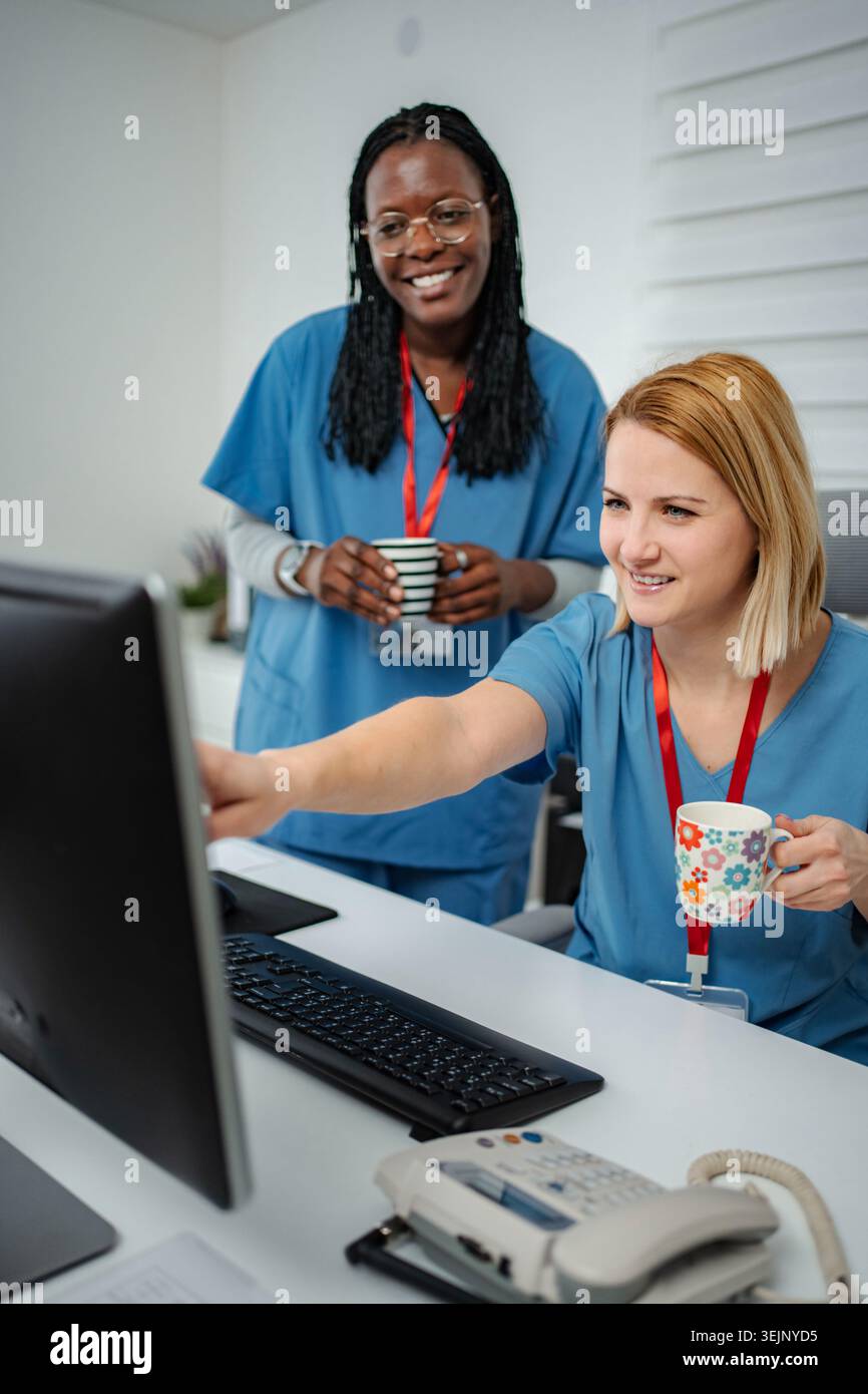 Nurses collaborating looking at computer screen in clinic Stock Photo