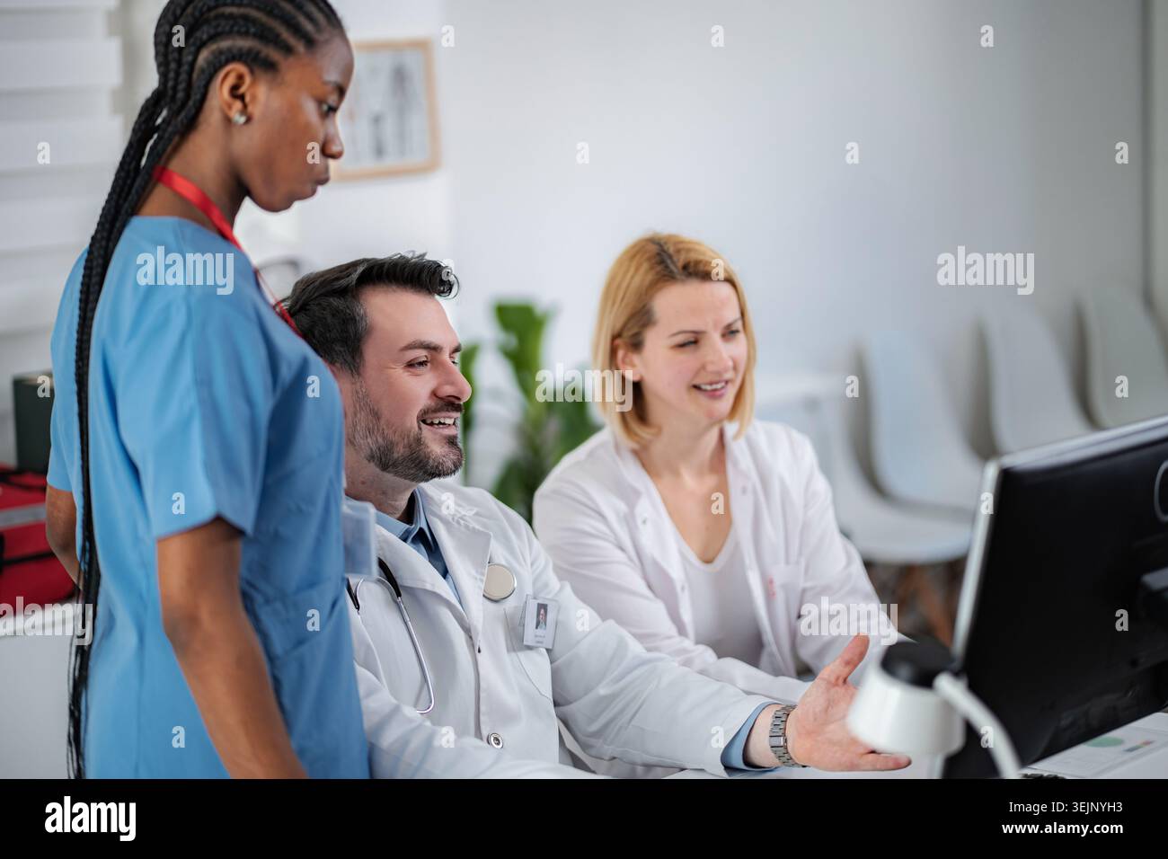 Medical professionals collaborating on computer while discussing patient information Stock Photo