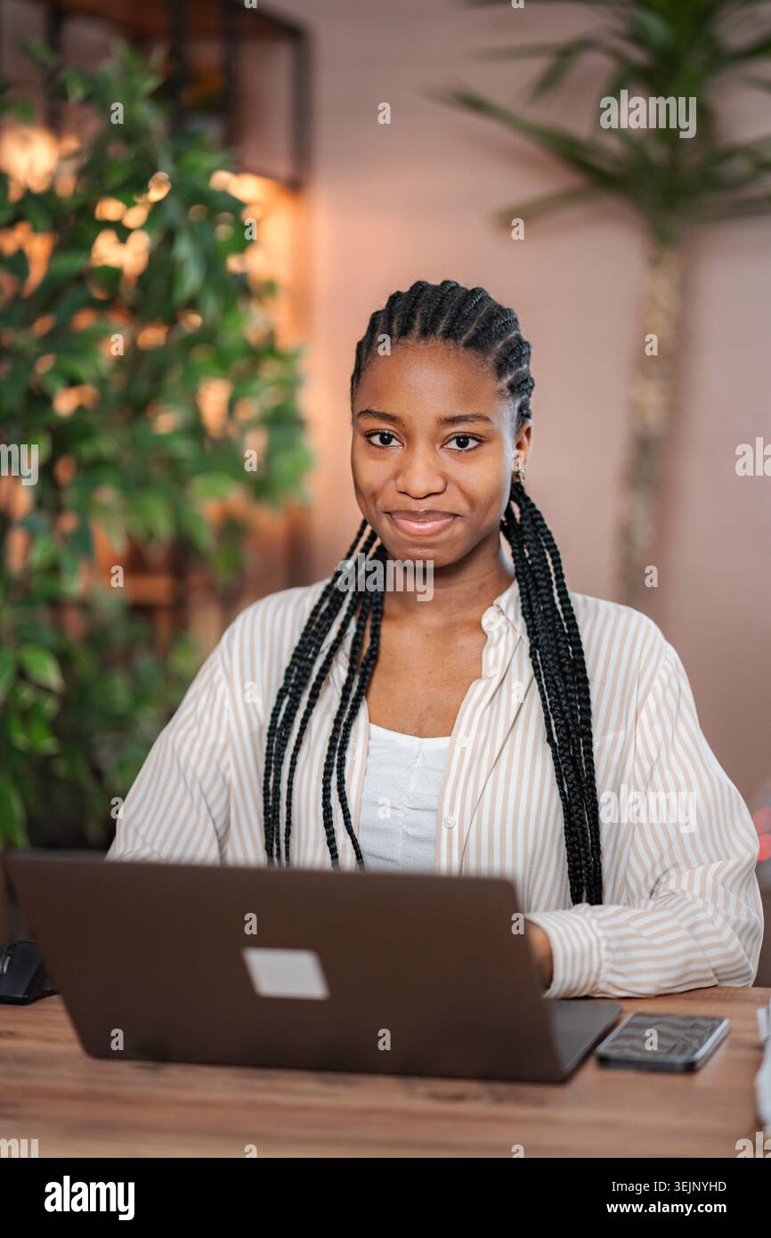 Young black woman smiling while working on laptop Stock Photo