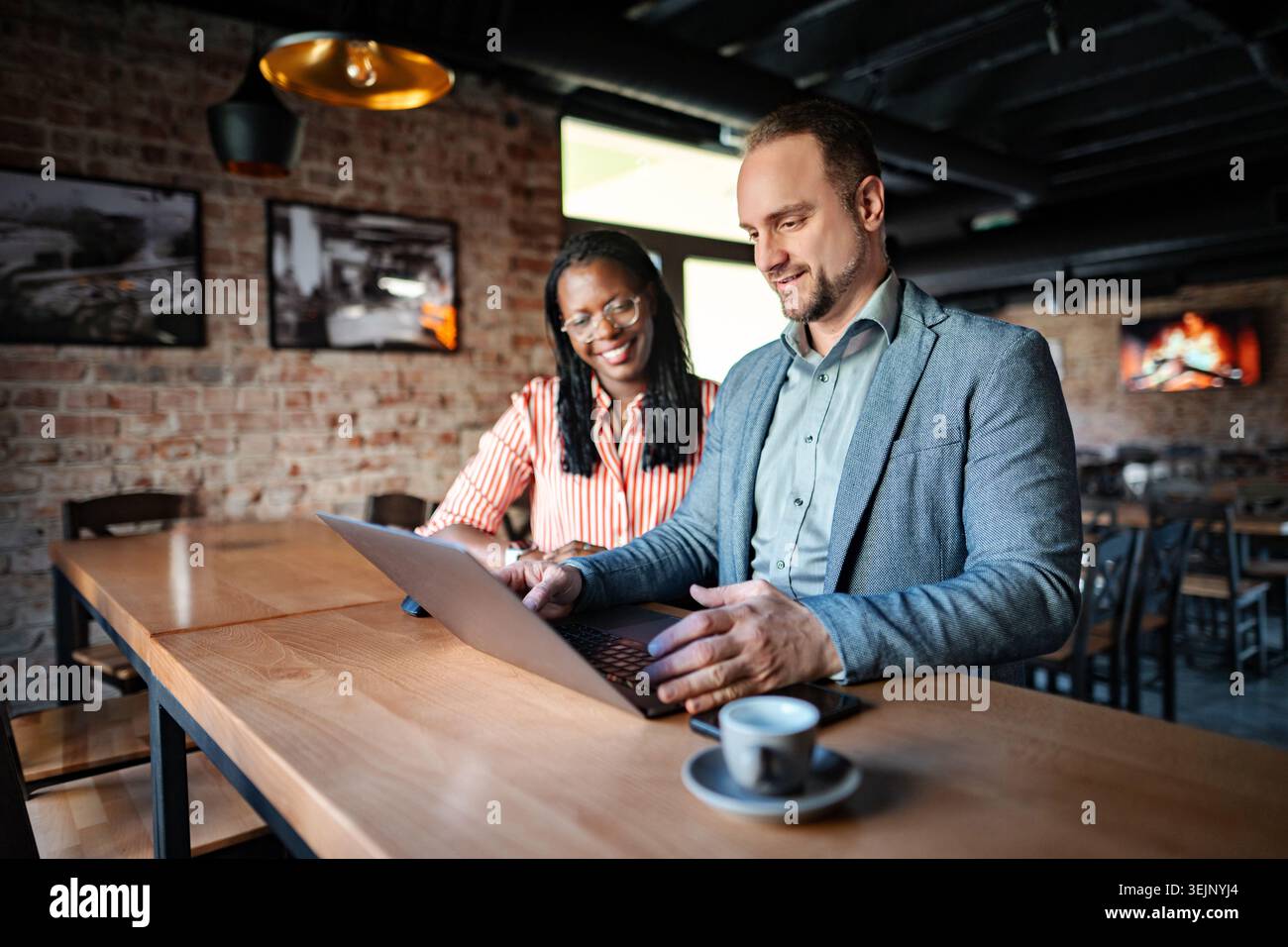 Diverse colleagues collaborating using laptop during coffee break Stock Photo