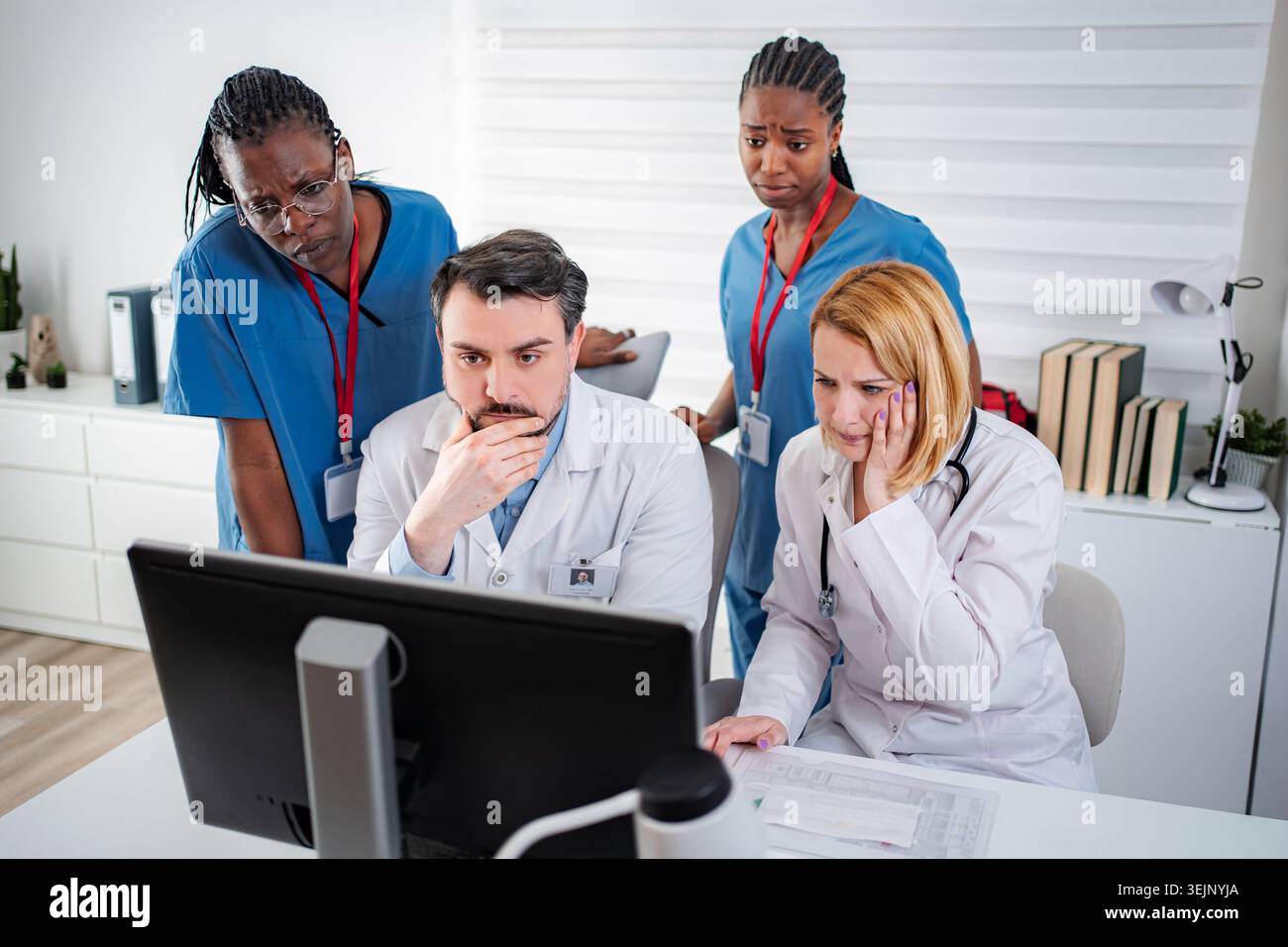 Medical team collaborating on urgent problem using computer Stock Photo