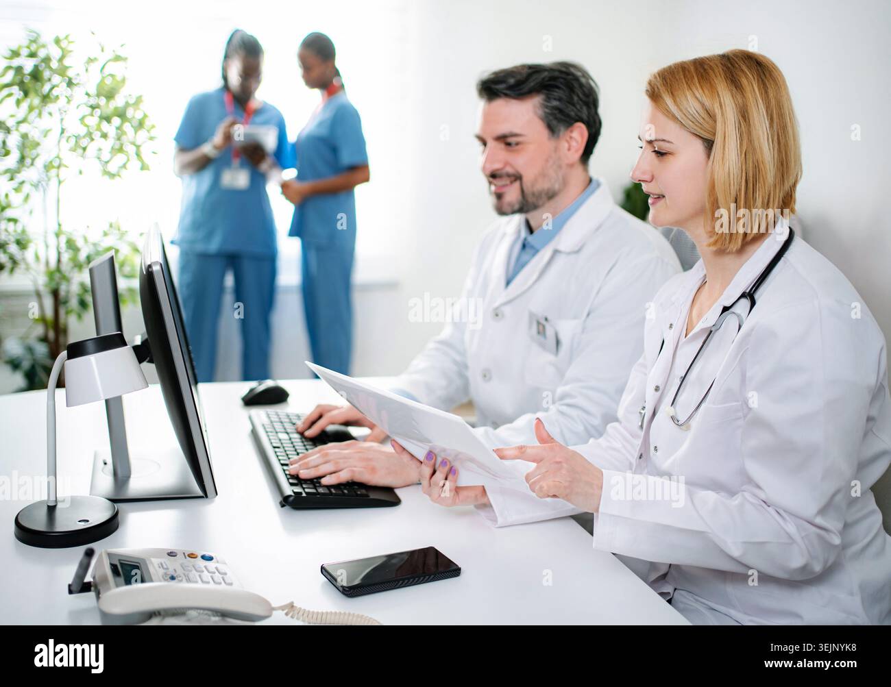 Medical team collaborating and checking documents on computer Stock Photo