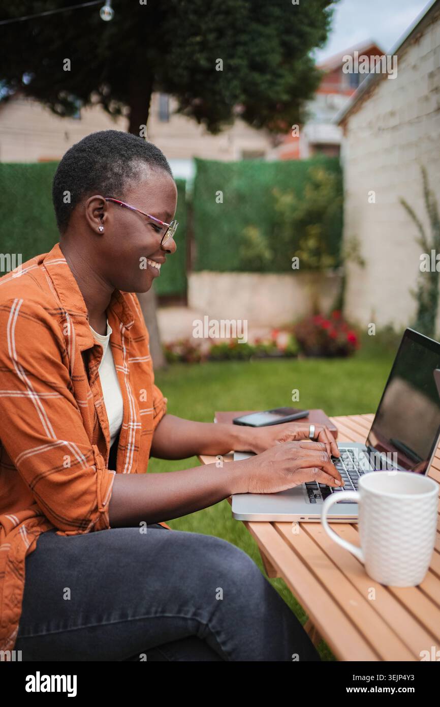 Smiling freelancer working on laptop in garden Stock Photo
