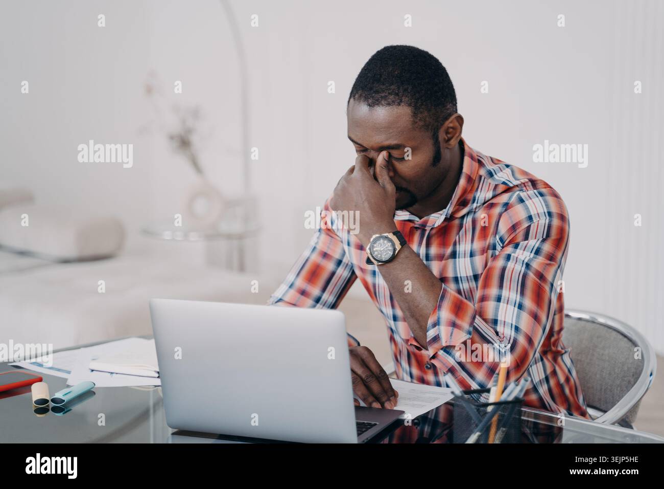 Focused tired african american businessman solves business problem working at laptop. Stress at work Stock Photo