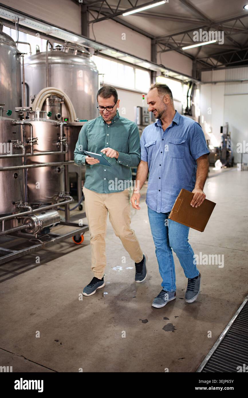 Brewery workers discussing production using tablet technology Stock Photo