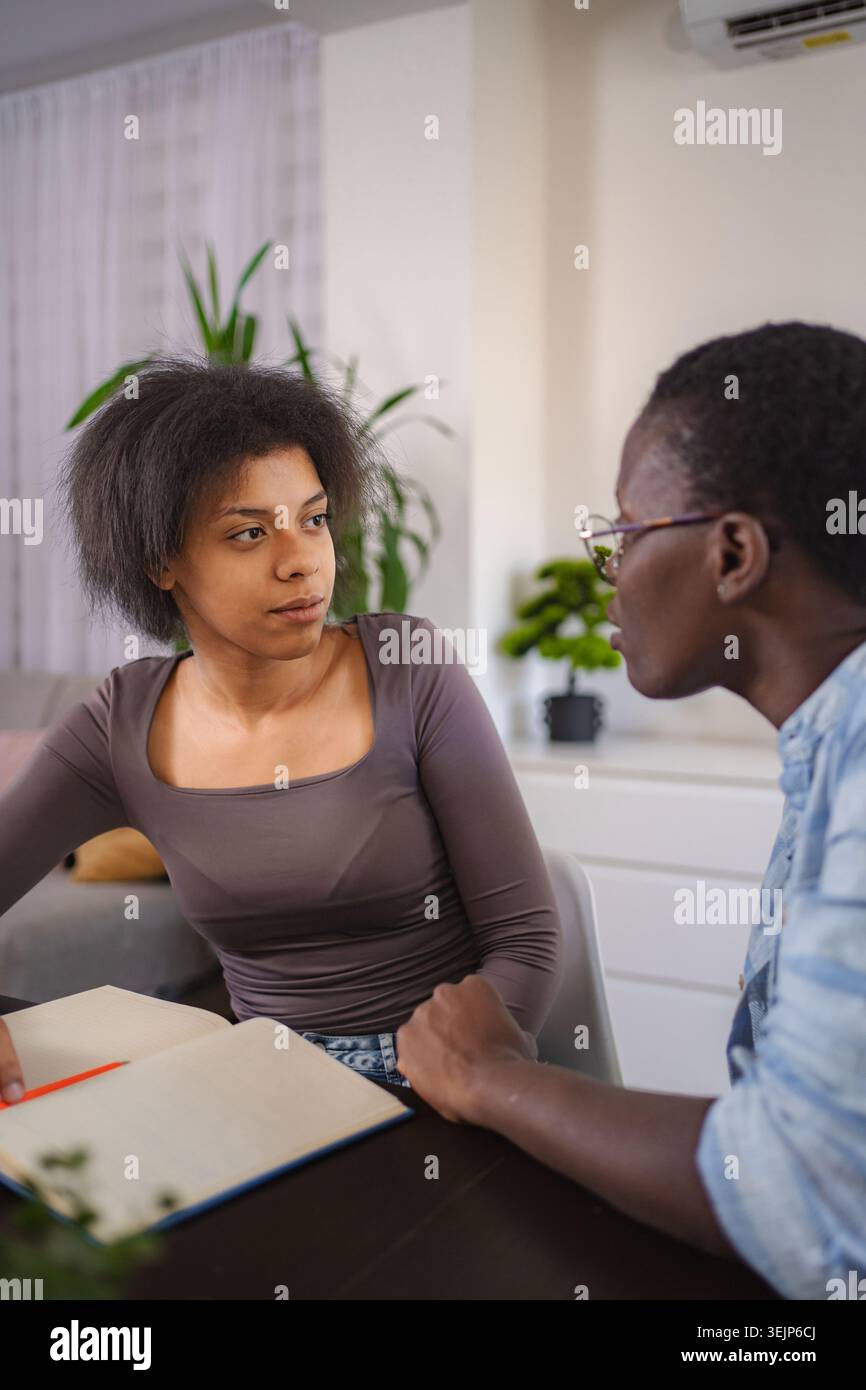 Young students studying together at home, taking notes and discussing Stock Photo