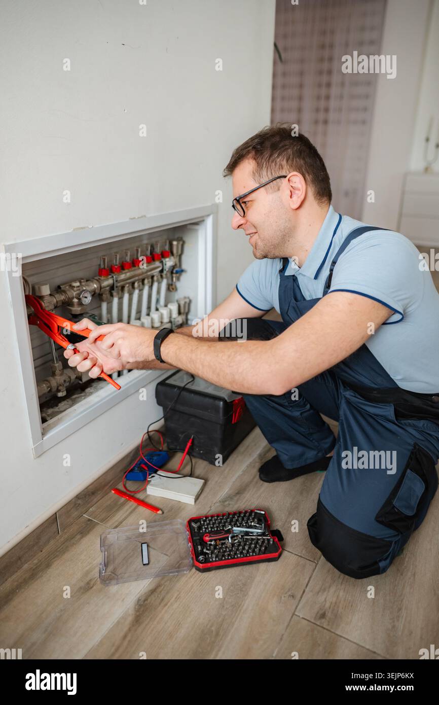 Technician working on heating system looking at pipes with tools Stock Photo