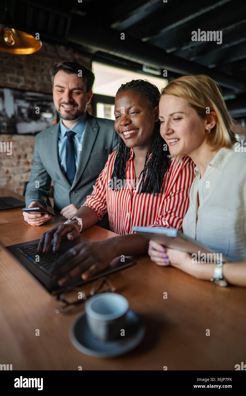 Diverse business team collaborating using laptop and tablet Stock Photo