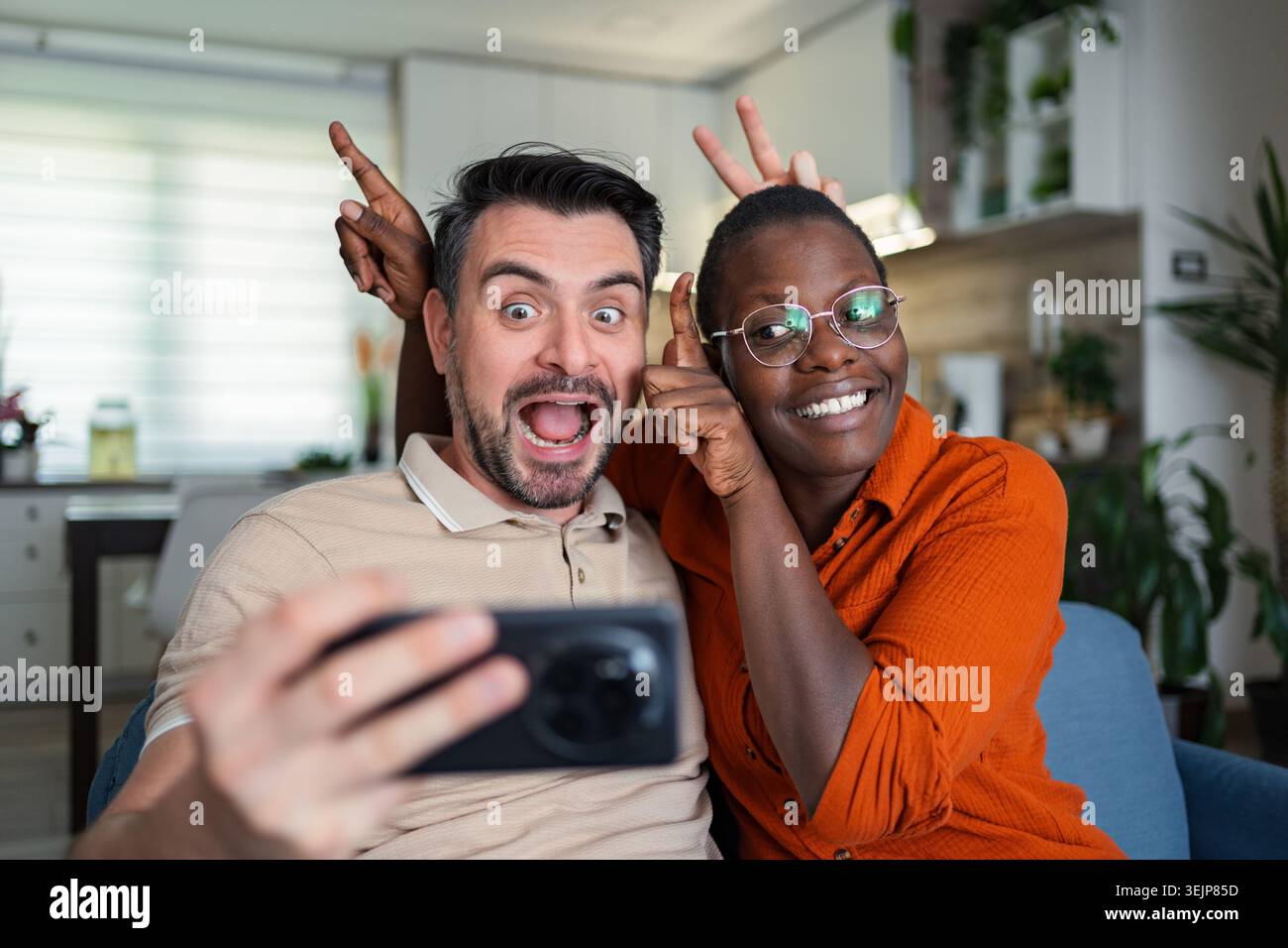 Playful couple taking a selfie making funny faces at home Stock Photo