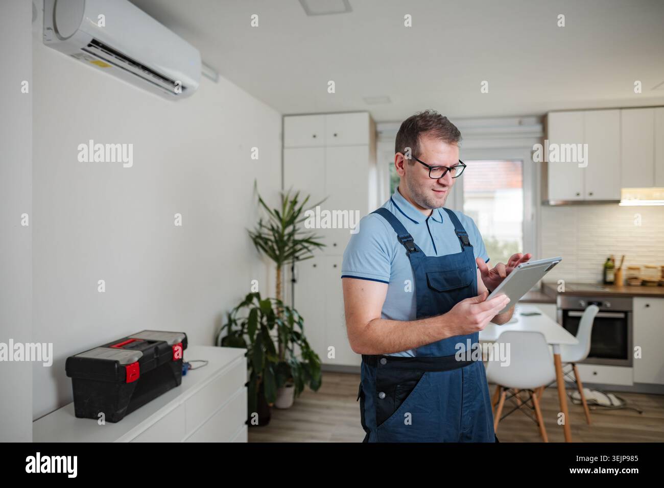 Technician checking air conditioner with digital tablet at home Stock Photo